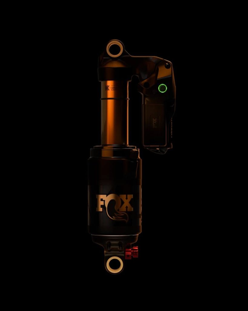 Premium Fox Factory electronic rear mountain bike shock dramatically lit against a dark background.