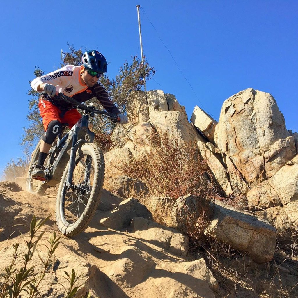A team rider putting a professionally tuned mountain bike to the test on a technical, rocky descent.